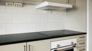 Vitt kök med beige luckor och vitt kakel.