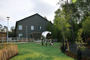 Grå byggnad med gräsmatta och ett konstverk framför