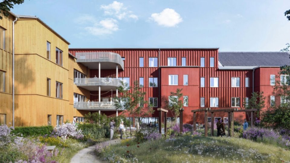 Gul och röd byggnad som sitter ihop med innegård utanför