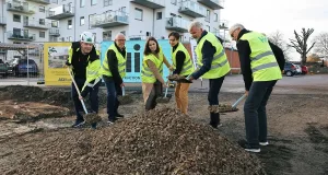Sex personer i byggväst tar första spadtag. 