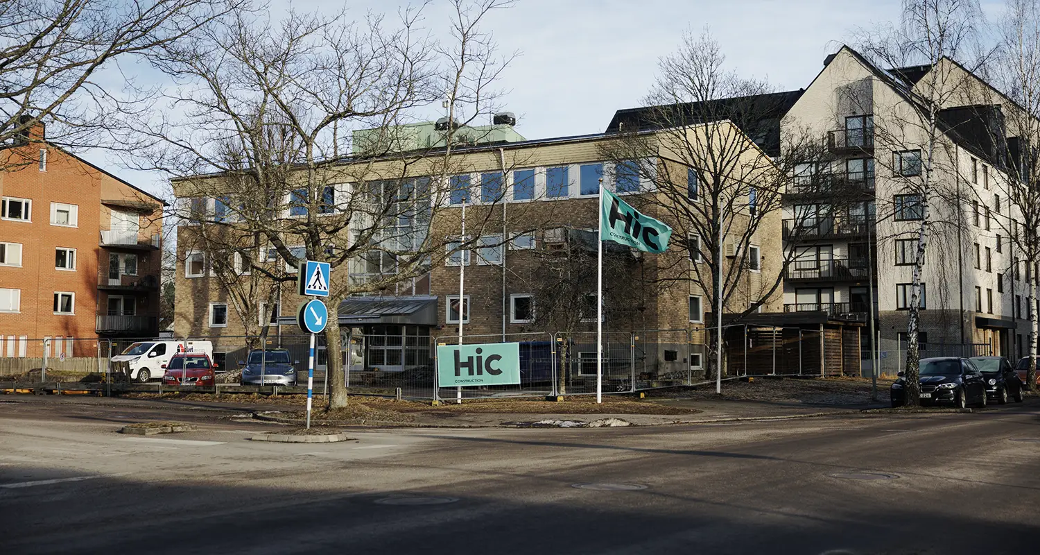 En gul tegelbyggnad med byggstängsel runt.